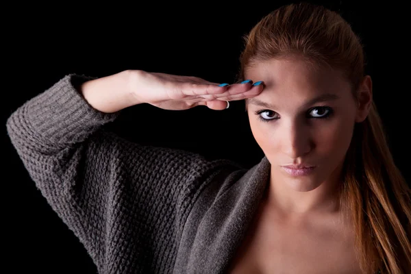 Beautiful woman saluting isolated on black background. Studio shot — Stock Photo, Image