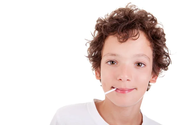Söt pojke med en godis på munnen ler, isolerad på vit, studio skott — Stockfoto