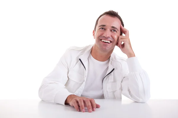 Ein lächelnder Mann mittleren Alters sitzt am Schreibtisch auf weißem Hintergrund. Studioaufnahme — Stockfoto