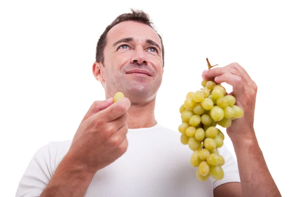 Hombre guapo comiendo una uva verde, aislado sobre fondo blanco. Captura de estudio . —  Fotos de Stock