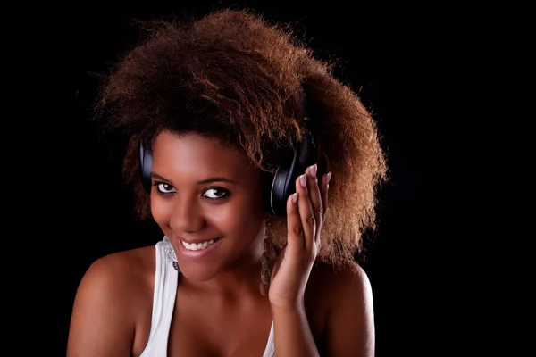 Όμορφη μαύρη γυναίκα ευτυχισμένη ακούγοντας μουσική στα ακουστικά, απομονώνονται σε μαύρο φόντο. Studio που γυρίστηκε. — Φωτογραφία Αρχείου