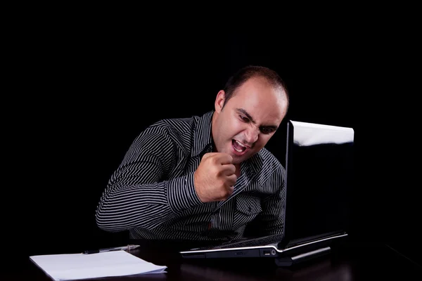 Wütender Geschäftsmann, der zum Computer blickt und Notizen macht, isoliert auf schwarzem Hintergrund. Studioaufnahme. — Stockfoto