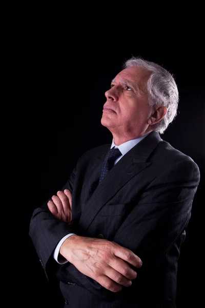 Portrait of a handsome mature businessman, looking up thinking, on black background, studio shot — Stock Photo, Image