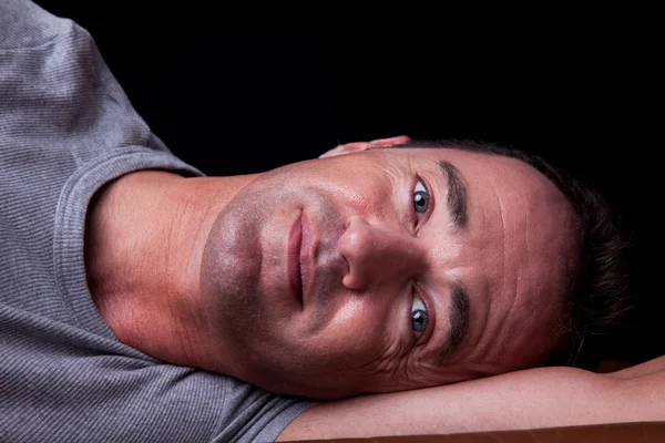 Portrait of a handsome middle-age man lying, on black background. Studio shot — Stock Photo, Image