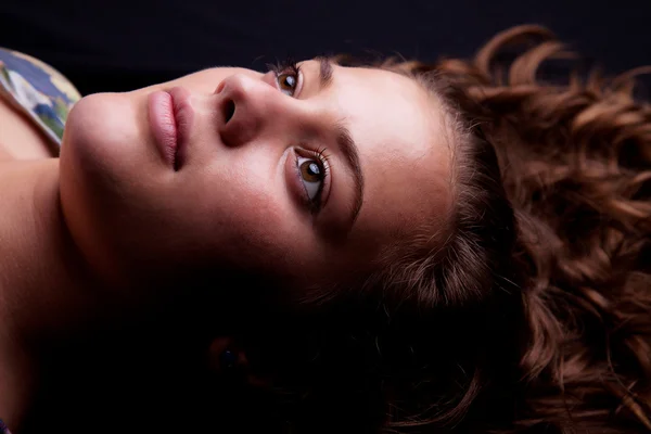 Красивая девушка лежит глядя вверх, изолированный на черном фоне. Снимок студии . — стоковое фото