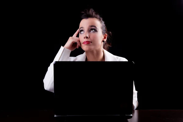 Гарна жінка на комп'ютері, думаючи, дивлячись вгору, ізольована на чорному тлі. Студійний знімок . — стокове фото