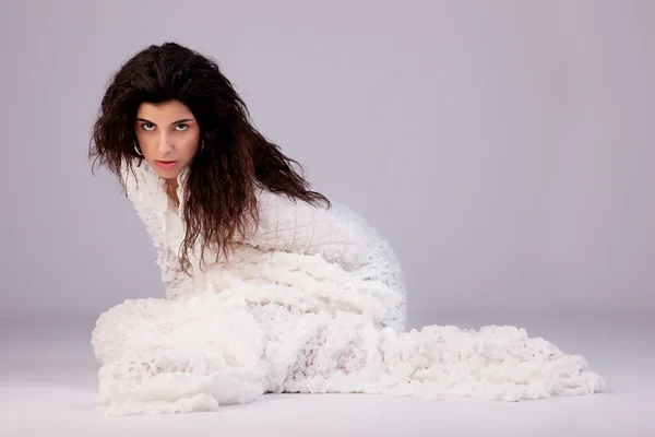 Bela jovem mulher sentada no chão, envolto em um cobertor branco, tiro estúdio — Fotografia de Stock