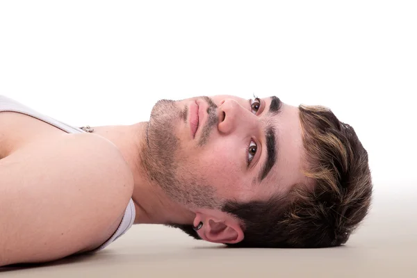 Portrait of a handsome man thinking lying on floor. Studio shot — Stock Photo, Image