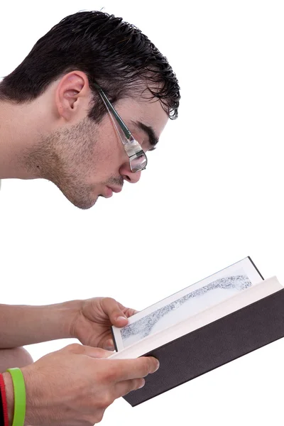 Young man with glasses seated reading a book, isolated on white, studio shot — Stock Photo, Image