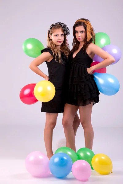 Two beautiful women, with colored ballons, studio shot. — Stock Photo, Image