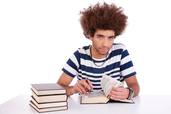 Handsome young man studying and reading a book on his desk, isolated on white, studio shot — Stock Photo, Image