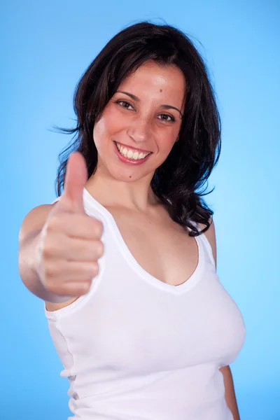 Young pretty women with thumb up, isolated on blue background. Studio shot. — Stock Photo, Image