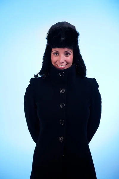 Schöne Frau lächelnd, mit Mütze und Mantel, isoliert auf blauem Hintergrund. Studioaufnahme. — Stockfoto