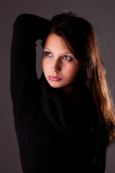 Unga och attraktiva kvinna som tittar upp, med händer som håller håret, studio skott — Stockfoto
