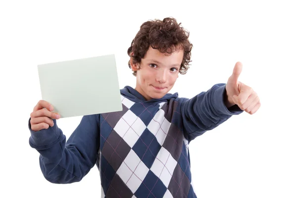 Netter Junge mit einer Pappe in der Hand, die Einwilligung gibt, mit erhobenem Daumen, isoliert auf weißem Hintergrund. Studioaufnahme. Stockbild