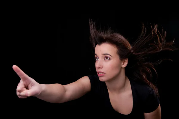 Bela jovem mulher com o cabelo no vento, dedo no ar, olhando para cima — Fotografia de Stock