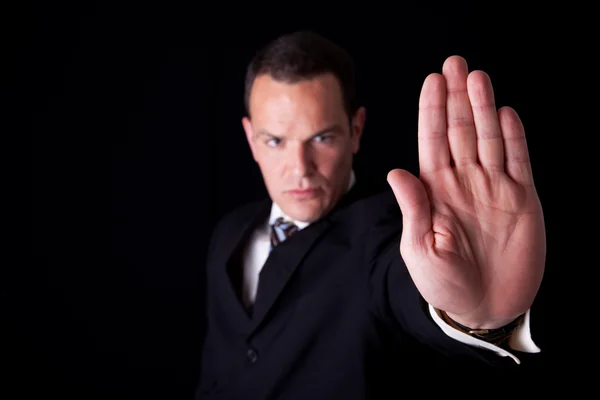 Бізнесмен з піднятою рукою, щоб зупинитися, ізольований на чорному тлі, студійний знімок — стокове фото