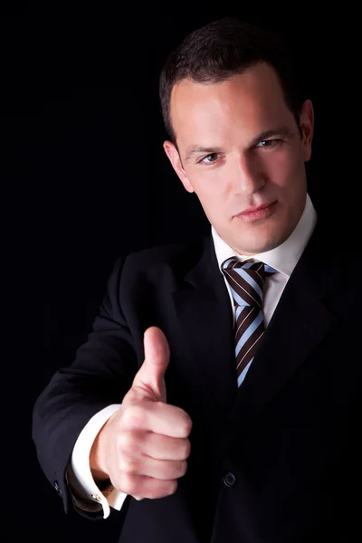 Hombre de negocios dando su consentimiento, con el pulgar hacia arriba, aislado sobre fondo negro. Captura de estudio . — Foto de Stock
