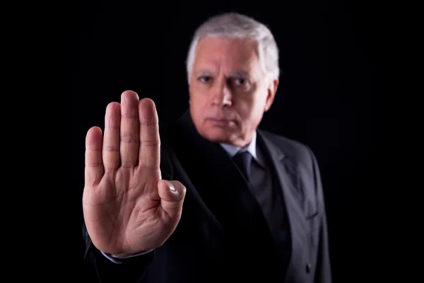 Vecchio uomo d'affari con la mano alzata in segnale per fermarsi, isolato su sfondo nero, Studio girato — Foto Stock