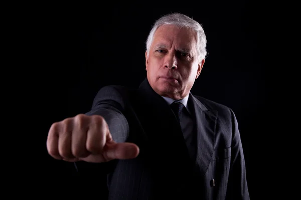 Oude zakenman met een hand met duimen midden op zwarte achtergrond, studio opname — Stockfoto