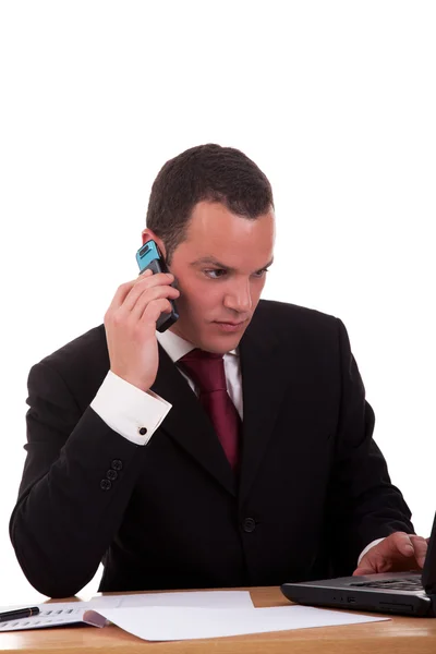 Geschäftsmann an einem Schreibtisch, der auf weißem Hintergrund isoliert telefoniert. Studioaufnahme. — Stockfoto