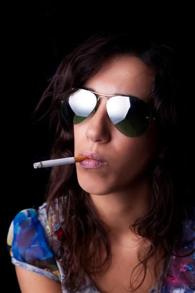 Morena jovem e sexy com cigarro e óculos de sol, isolada em fundo preto. Estúdio — Fotografia de Stock
