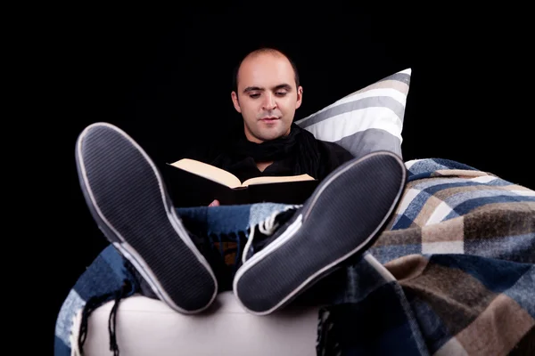 Man lying on the sofa reading a book, isolated on black, studio shot. — Stock Photo, Image