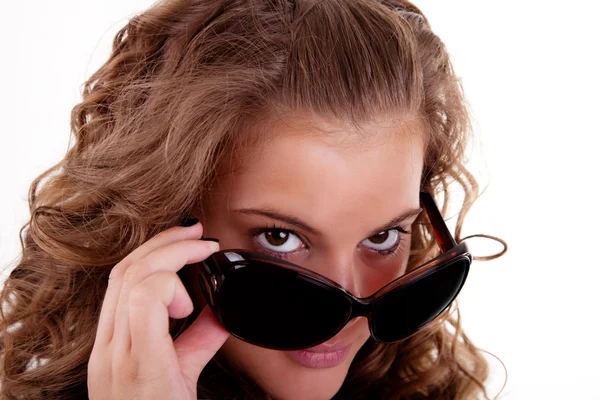 Porträt einer jungen Frau, die über ihre Sonnenbrille blickt, isoliert auf weißem Hintergrund. Studioaufnahme — Stockfoto