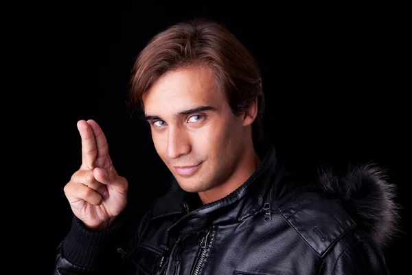 Portrait of a young man with two fingers up, in autumn and winter clothes — Stock Photo, Image