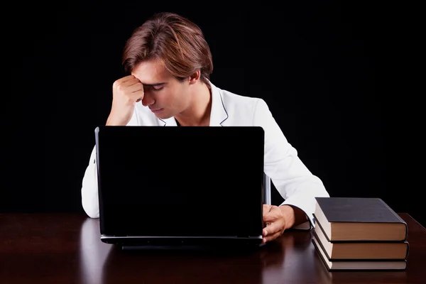 Unavený mladý podnikatel v počítači na černém pozadí. Studio záběr — Stock fotografie