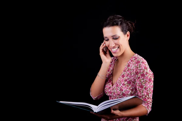Beautiful woman on the phone reading information, isolated on black background — Stock Photo, Image