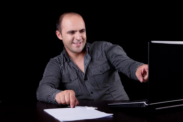 Geschäftsmann lacht und blickt auf Computer, isoliert auf schwarzem Hintergrund. Studioaufnahme. — Stockfoto