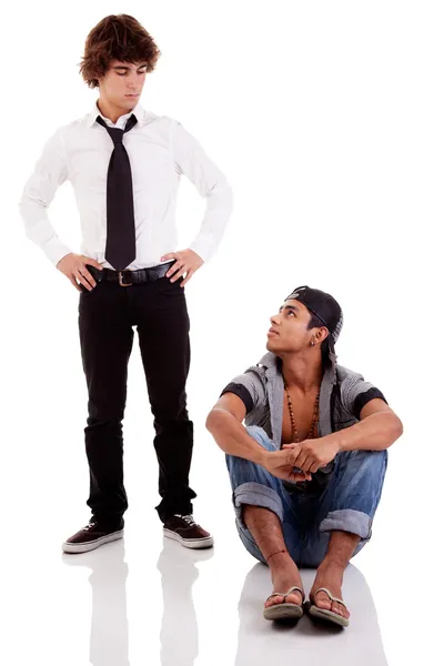 Двоє чоловіків різної етнічної приналежності, один сидить, дивлячись на інший стоячи, ізольовані на білому, студійний знімок — стокове фото