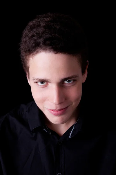 Cute boy, smiling and looking to camera on black, studio shot