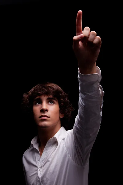Jeune homme levant les yeux vers la lumière et pointant du doigt - signe de foi, isolé sur noir, plan studio — Photo