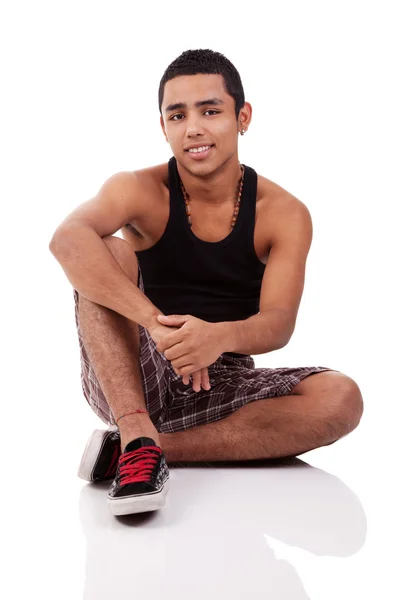 Joven y guapo latino, sentado en el suelo aislado sobre fondo blanco, plano de estudio —  Fotos de Stock