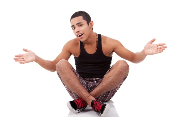 Молодий чоловік з відкритими руками, сидить на підлозі, ізольований на білому, студійний знімок — стокове фото