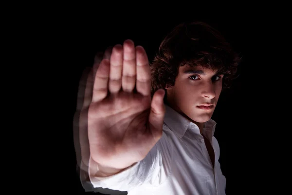 Niedlicher Junge mit erhobener Hand zum Anhalten, isoliert auf schwarzem Hintergrund, Studioaufnahme — Stockfoto