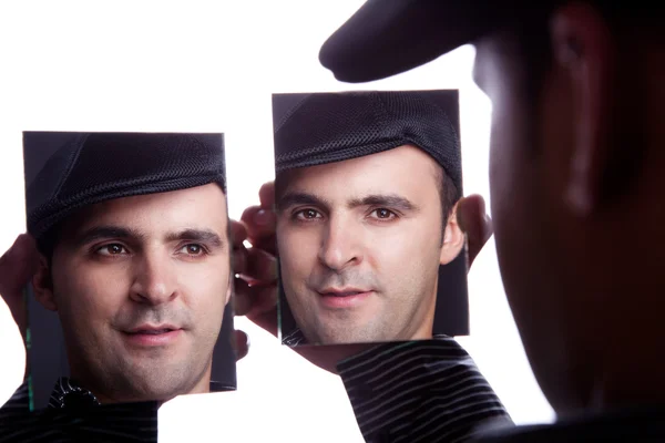 Um homem, com o rosto no espelho, isolado em branco, filmado em estúdio — Fotografia de Stock
