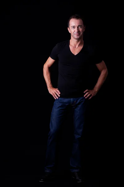 Portrait of a handsome middle-age man smiling, on black background. Studio shot — Stock Photo, Image