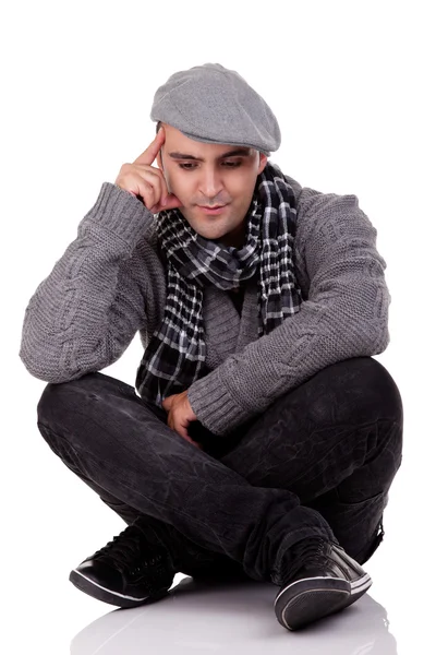 Portrait of a young man sitting on the floor, thinking and looking down — Stock Photo, Image