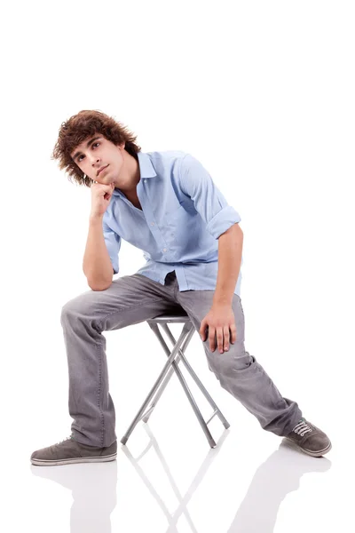 Молодой человек, сидящий на скамейке, изолированный на белом фоне — стоковое фото