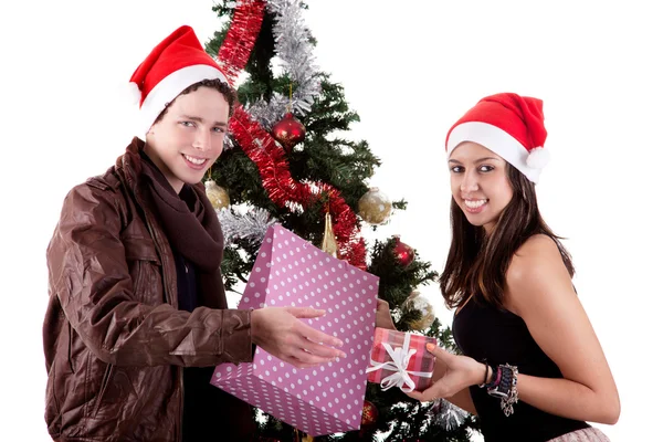 Щаслива молода пара, відкриваючи подарунки біля ялинки, ізольована на білому — стокове фото