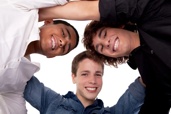 Tre unge menn med ulik farge, som ser mot kameraet og smiler, utsikt nedenfra – stockfoto