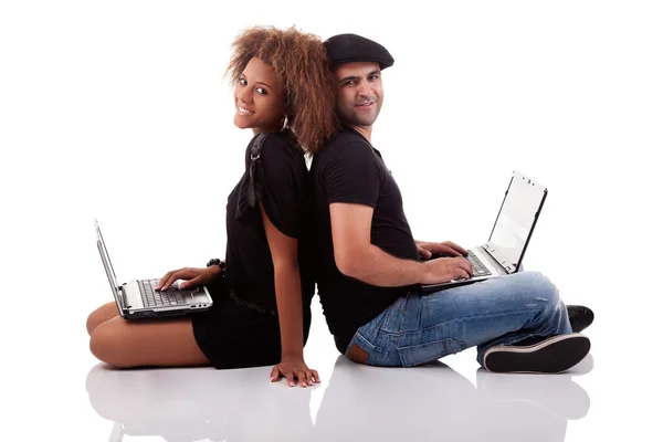 Пара позаду, сидячи на підлозі, з комп'ютерами, ізольовані на білому тлі, студійний знімок Стокове Зображення