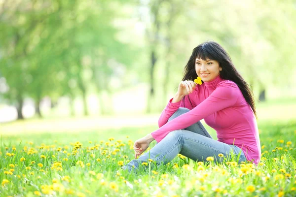 Niedliche Frau im Park mit Löwenzahn — Stockfoto