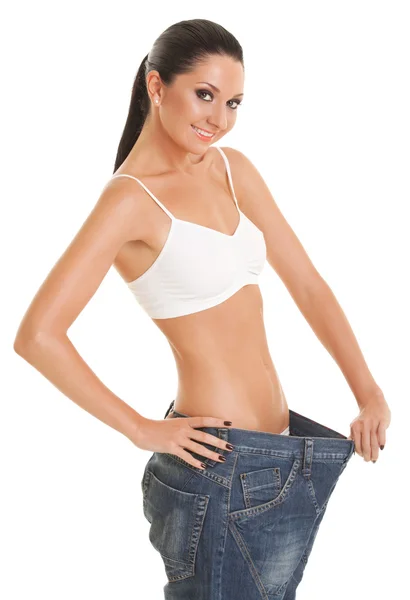 Mulher engraçada mostra sua perda de peso usando um jeans velho, isola — Fotografia de Stock