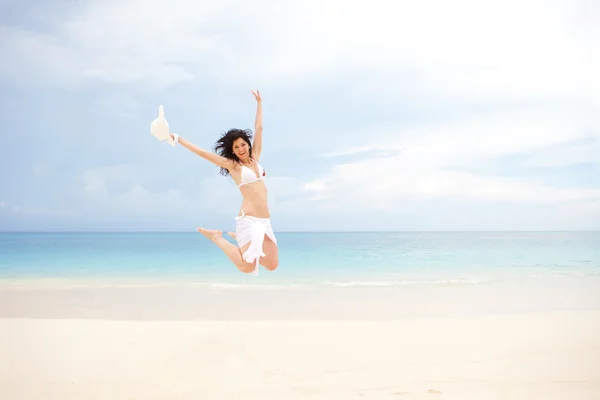 Gelukkig jonge vrouw springen op het strand van zee — Stockfoto