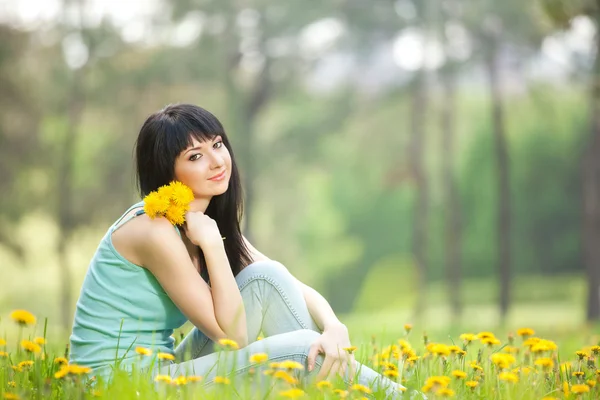 Cute woman in the park with dandelions — Zdjęcie stockowe