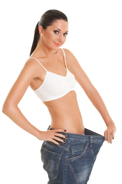 Pretty woman shows her weight loss by wearing an old jeans — Stock Photo, Image
